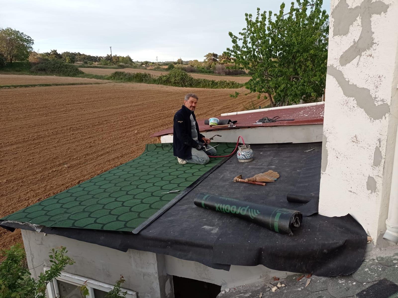 Usta, su yalıtım örtüsü serilmiş çatıya yeşil shingle kaplama uyguluyor