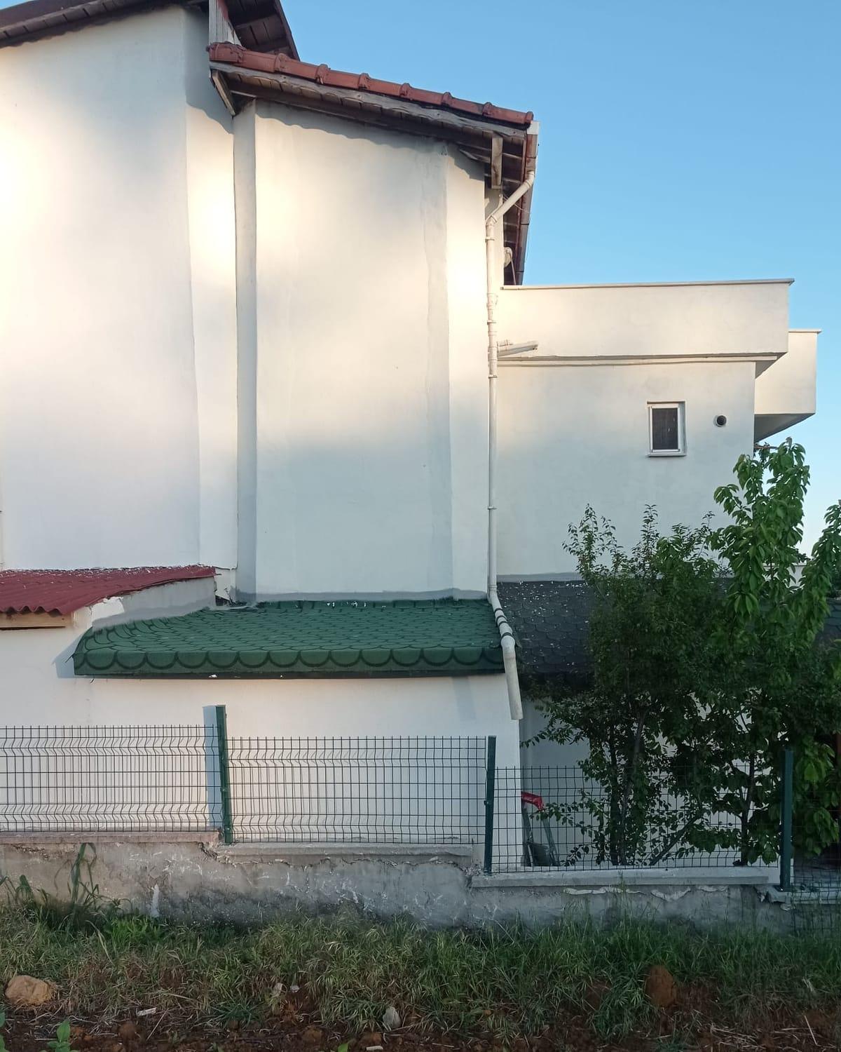 Sonrası: duvarları tamamlanmış ve yeşil shingle çatıyla kapatılmış ek bina